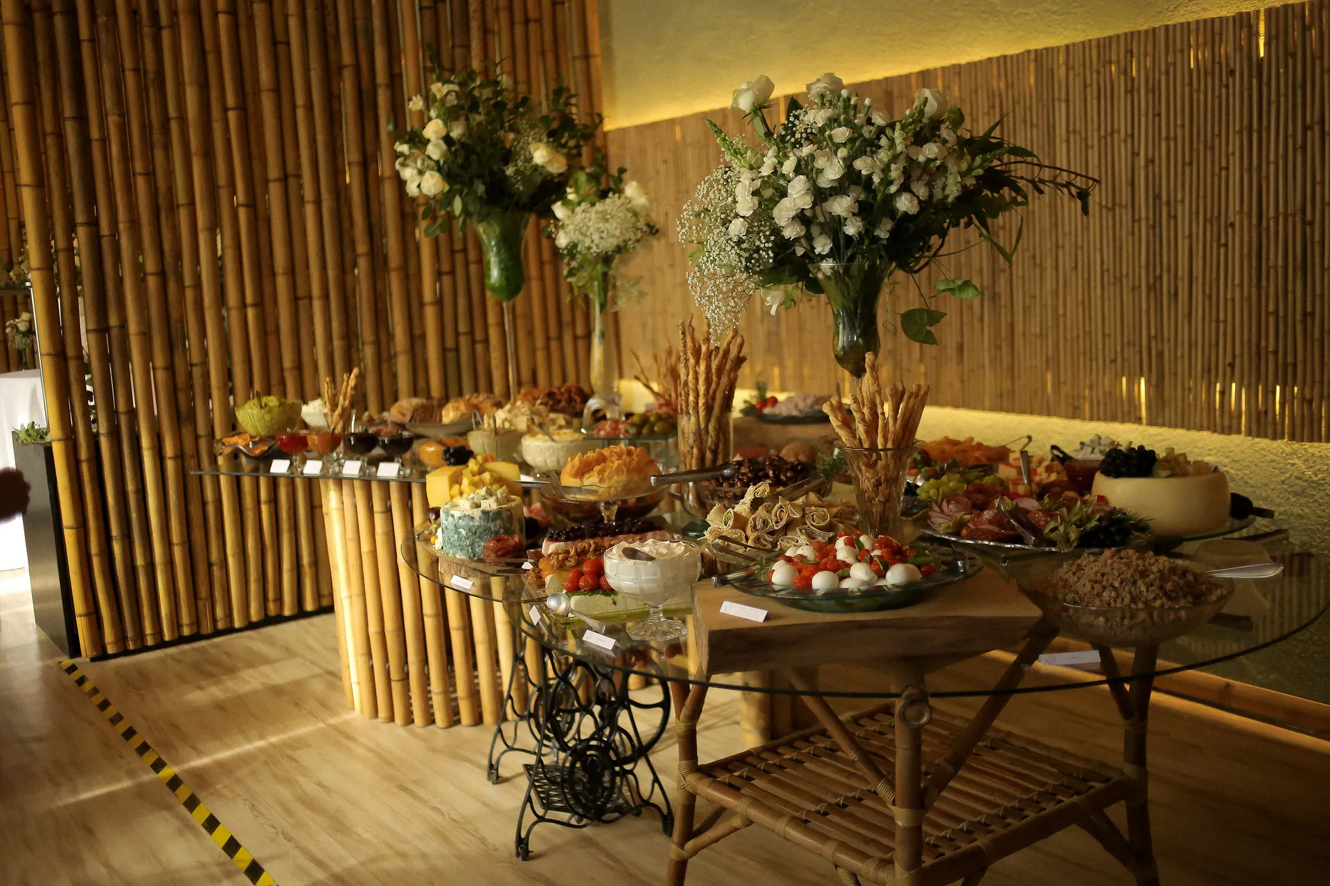 Buffet de casamento com arranjos florais e decoração de bambu