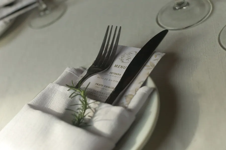 Menu impresso sobre guardanapo com talheres e ramo de alecrim