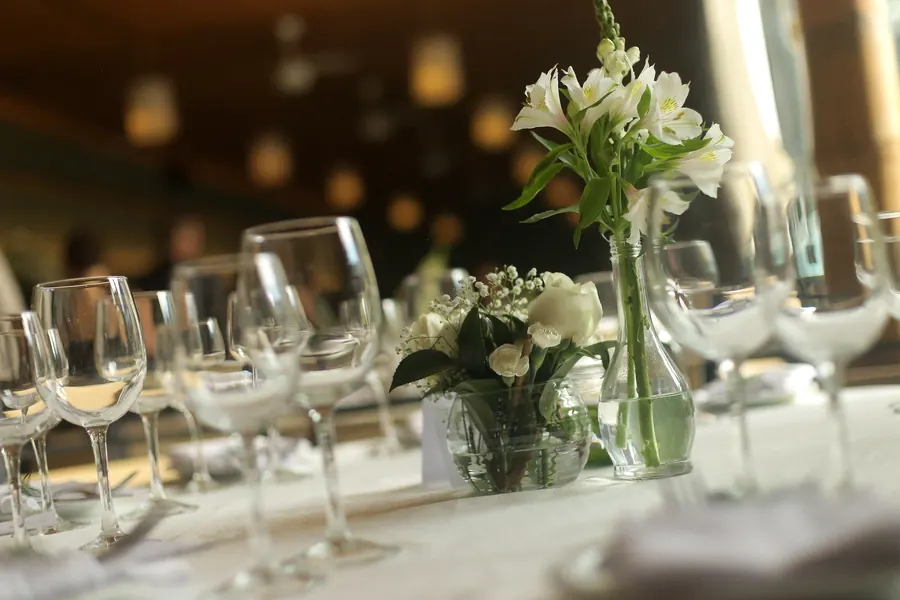 Detalhe de taças de cristal e arranjo de flores brancas